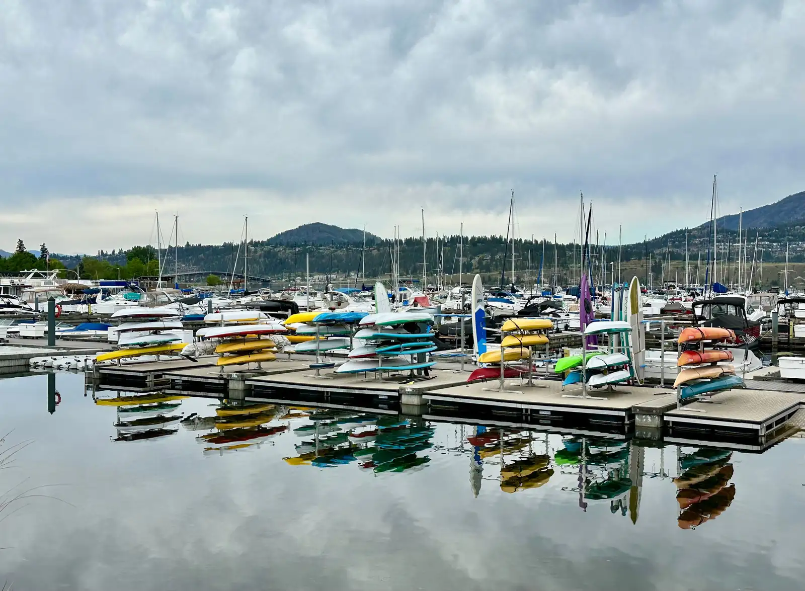 Colourful kayaks and boats reflected at a marina in Kelowna on Okanagan Lake