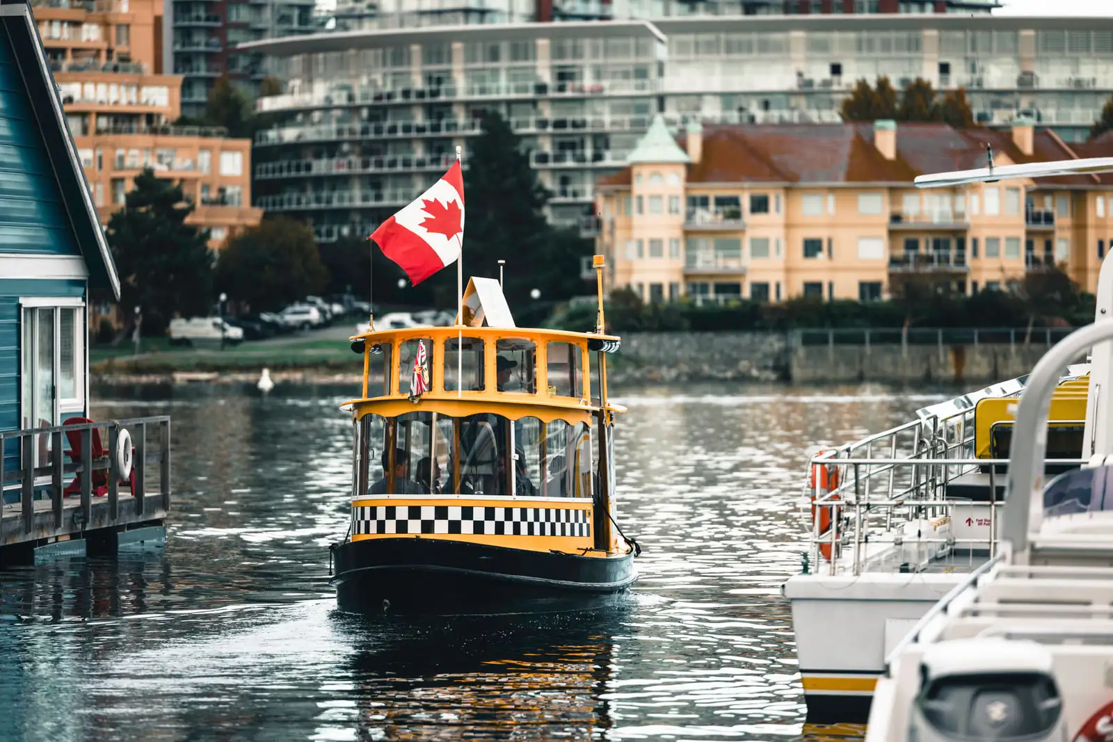 A small yellow harbour ferry with a Canadian flag in Victoria’s harbour